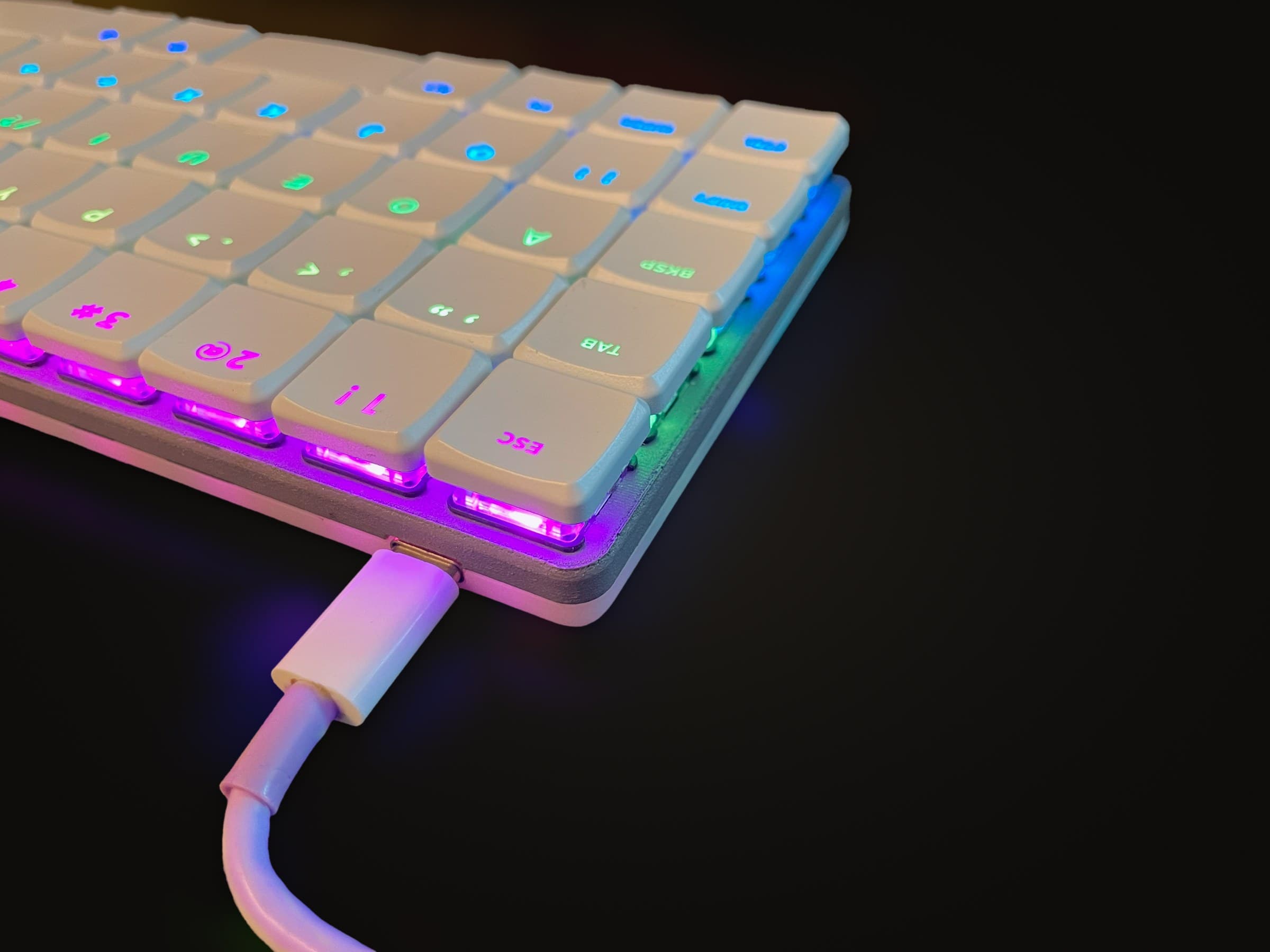 The Breeze V1 lit in a rainbow, a white USB-C cable plugged into its back edge.